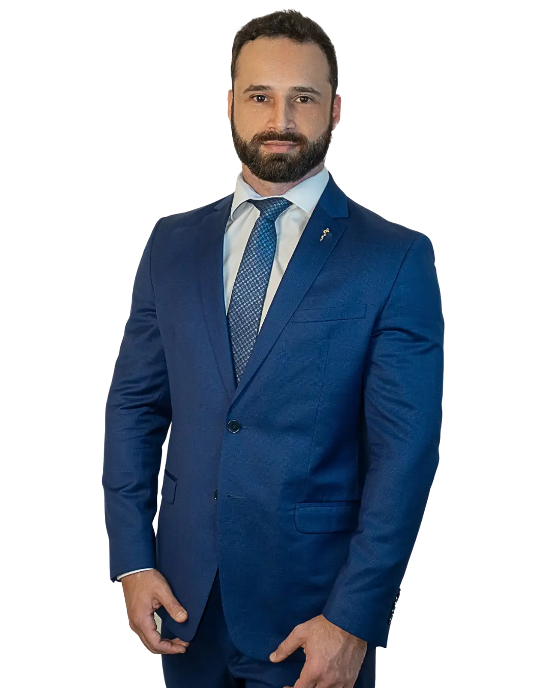 Homem em pé, vestindo terno azul com camisa branca e gravata azul, olhando para a câmera com expressão séria e postura confiante.