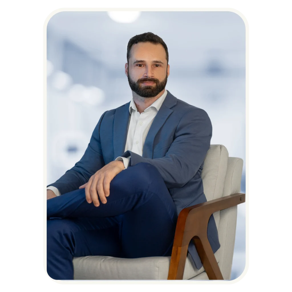 Dr. Raian Matias, endocrinologista, em retrato profissional sentado de terno azul, representando confiança e atendimento especializado em saúde.