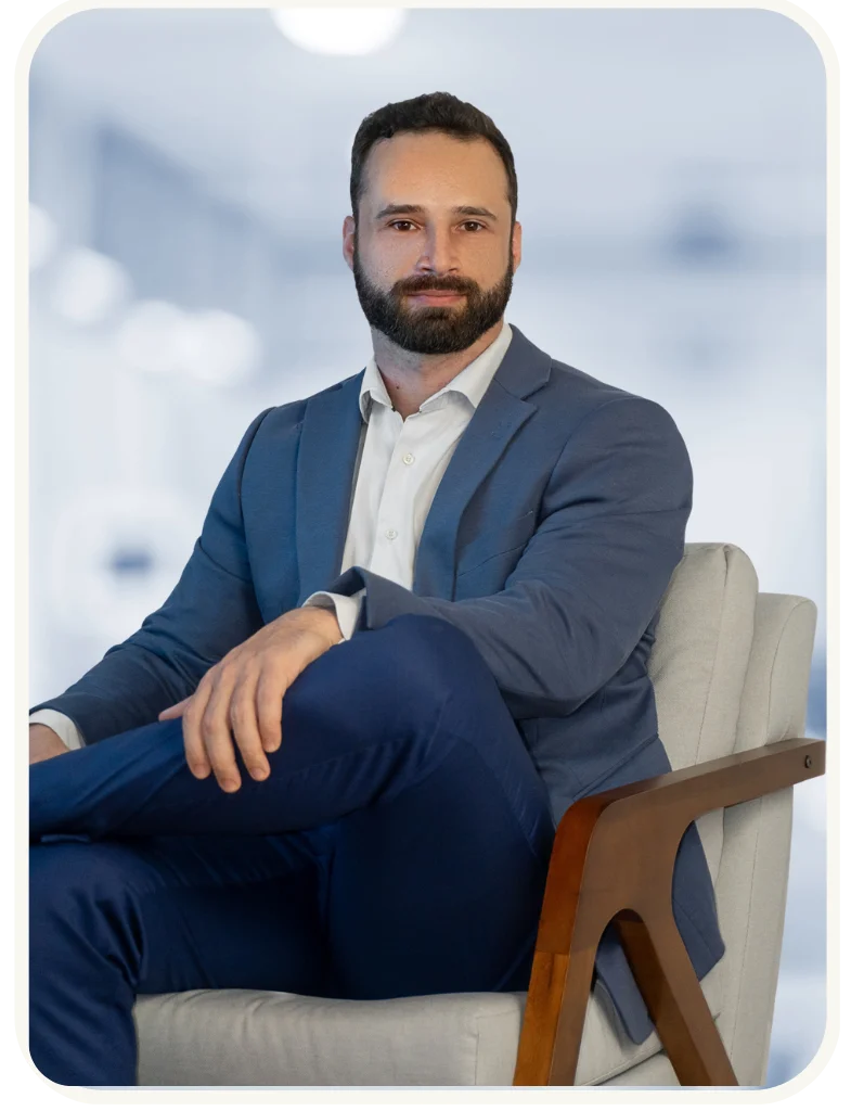 Dr. Raian Matias, endocrinologista, em retrato profissional sentado de terno azul, representando confiança e atendimento especializado em saúde.